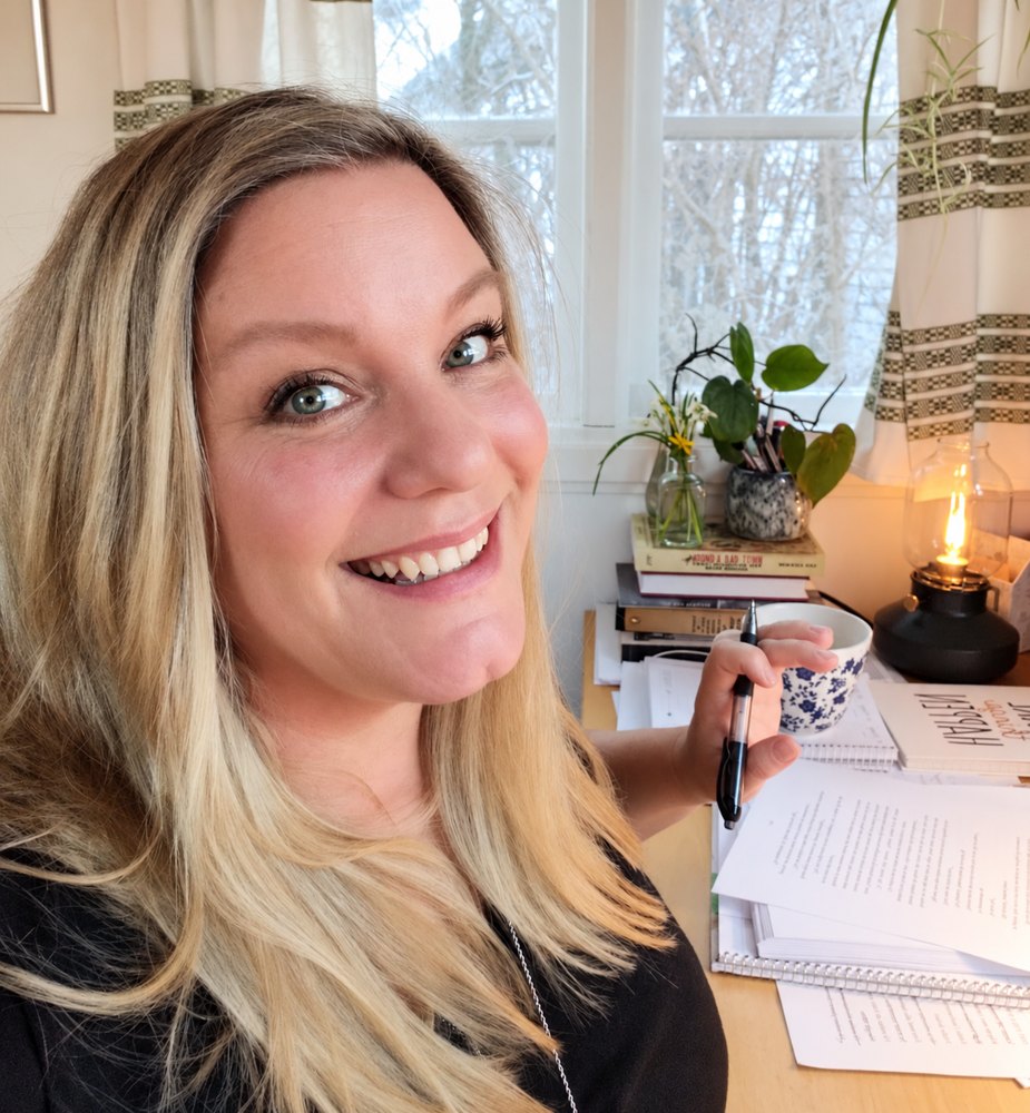 Sofie Bjarup vid skrivbordet med manus, en kopp te och en fotogenlampa